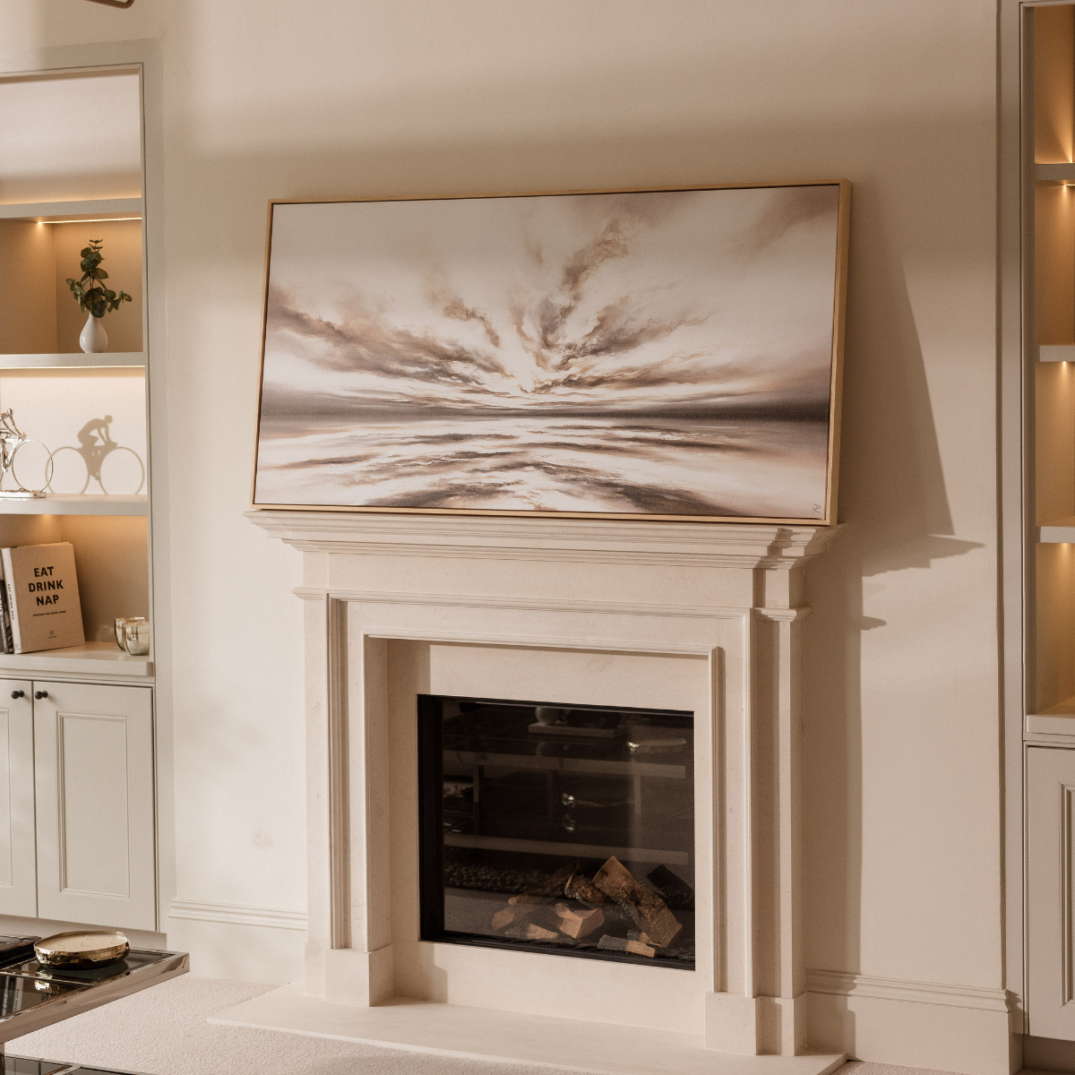 Beige fireplace with a large abstract painting above it in a home setting.